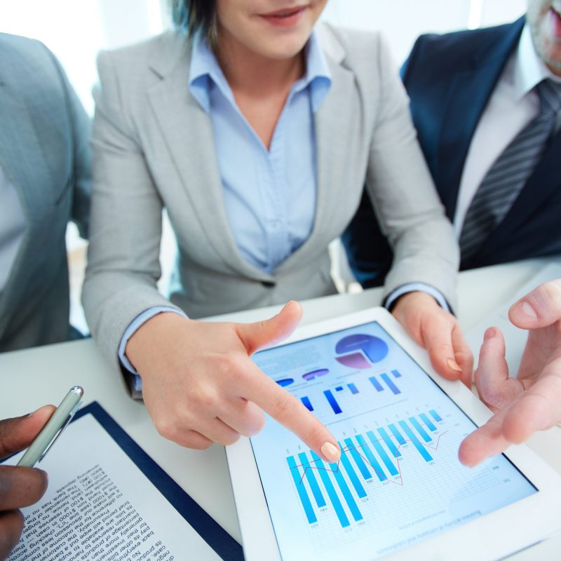 Image of human hands during discussion of business document in touchscreen at meeting